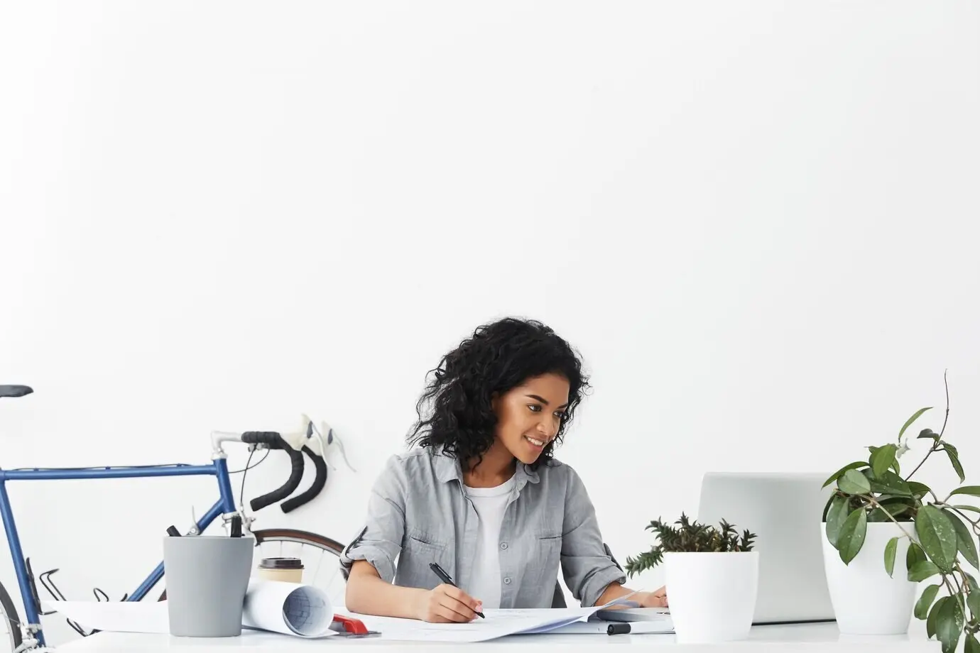 Schöne Designmitarbeiterin mit voluminösem dunklem Haar, die ein lässiges Hemd trägt.